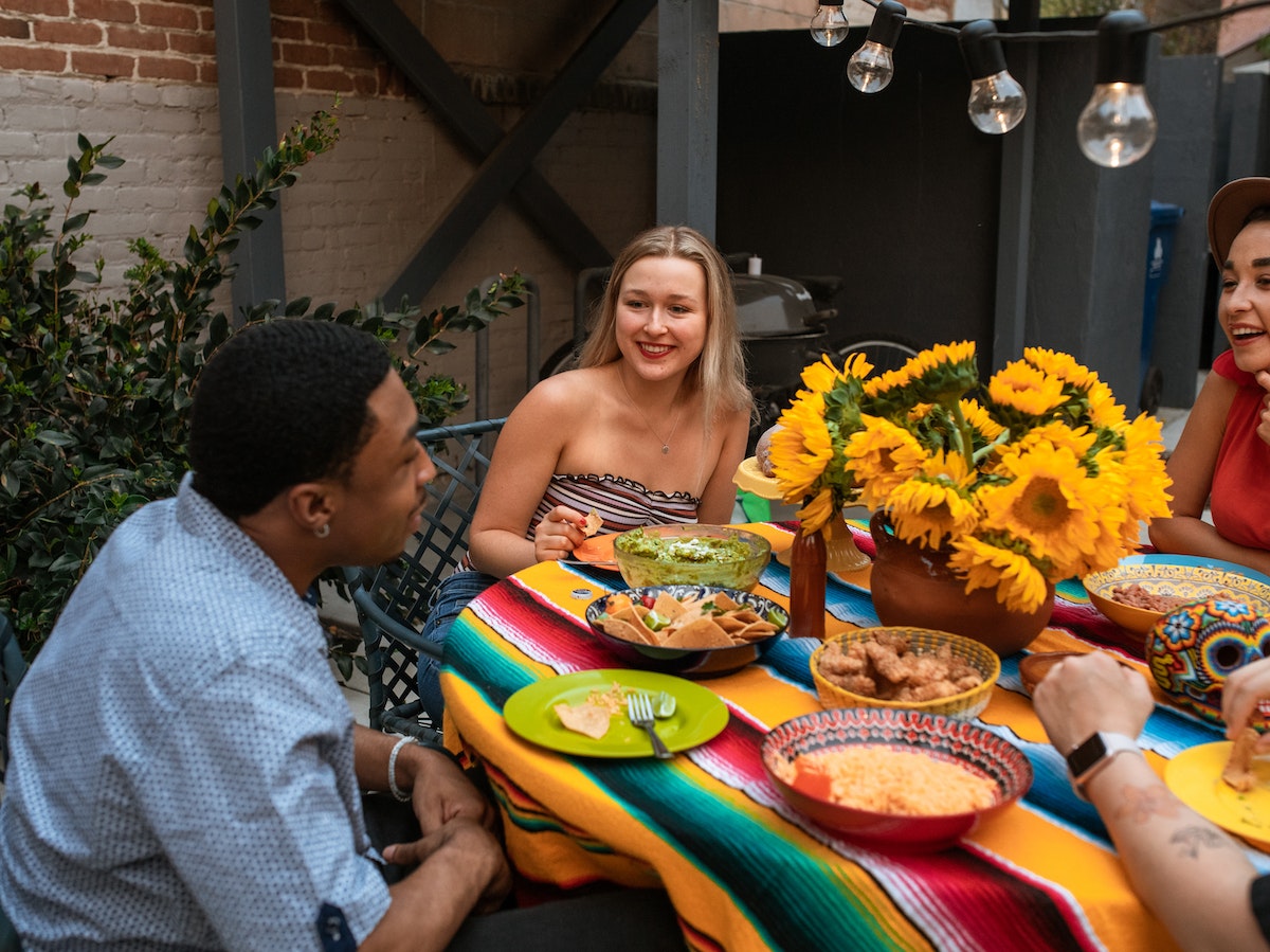 amigos sonrientes sentados en la mesa probando comida mexicana