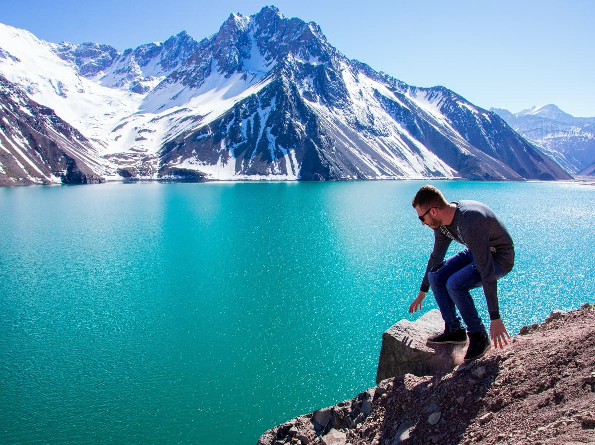 Tiempo para relajarse sentado en el suelo y mirando la belleza del Embalse El Yeso, Cordillera de los Andes en Chile