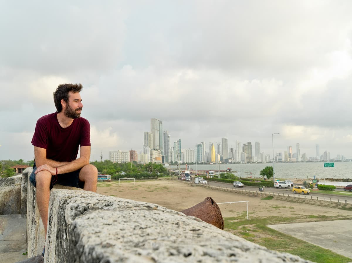 Vista panorámica del hombre que viaja en Cartagena de Indias. Vista horizontal del hombre de pasión por los viajes que viaja con el horizonte de Bocagrande en el fondo. Concepto de viaje a Colombia.