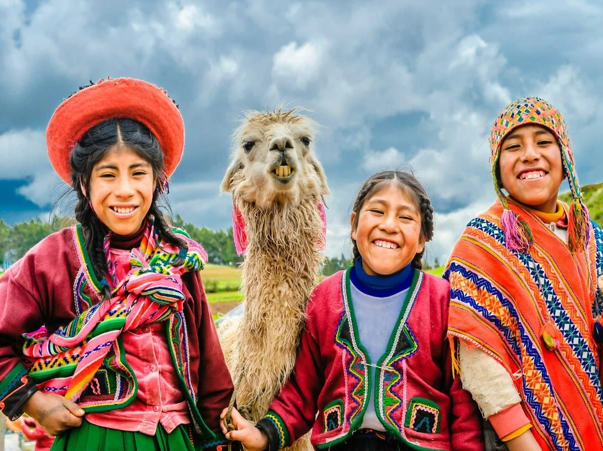 chicas sonriendo junto a una llama en Cusco Peru